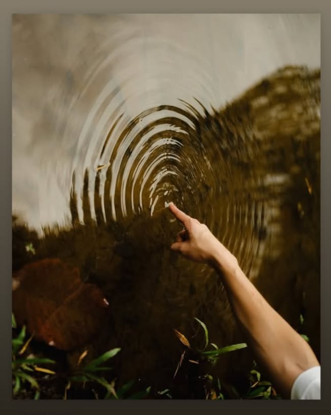 Una mano incontra cerchi concentrici sulla superficie dell’acqua